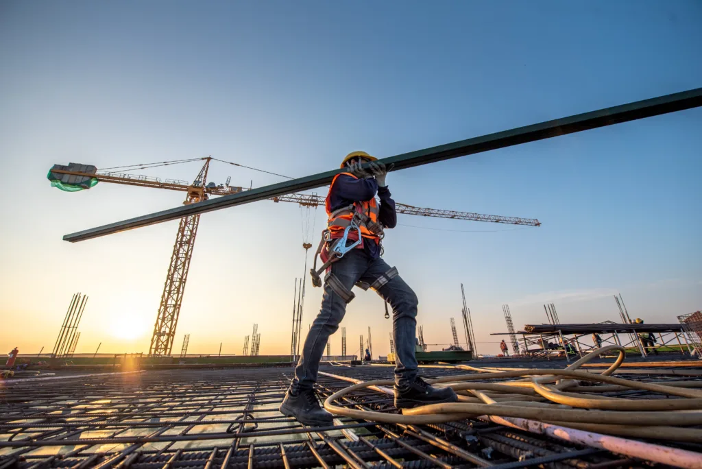 Construction worker carrying iron beam