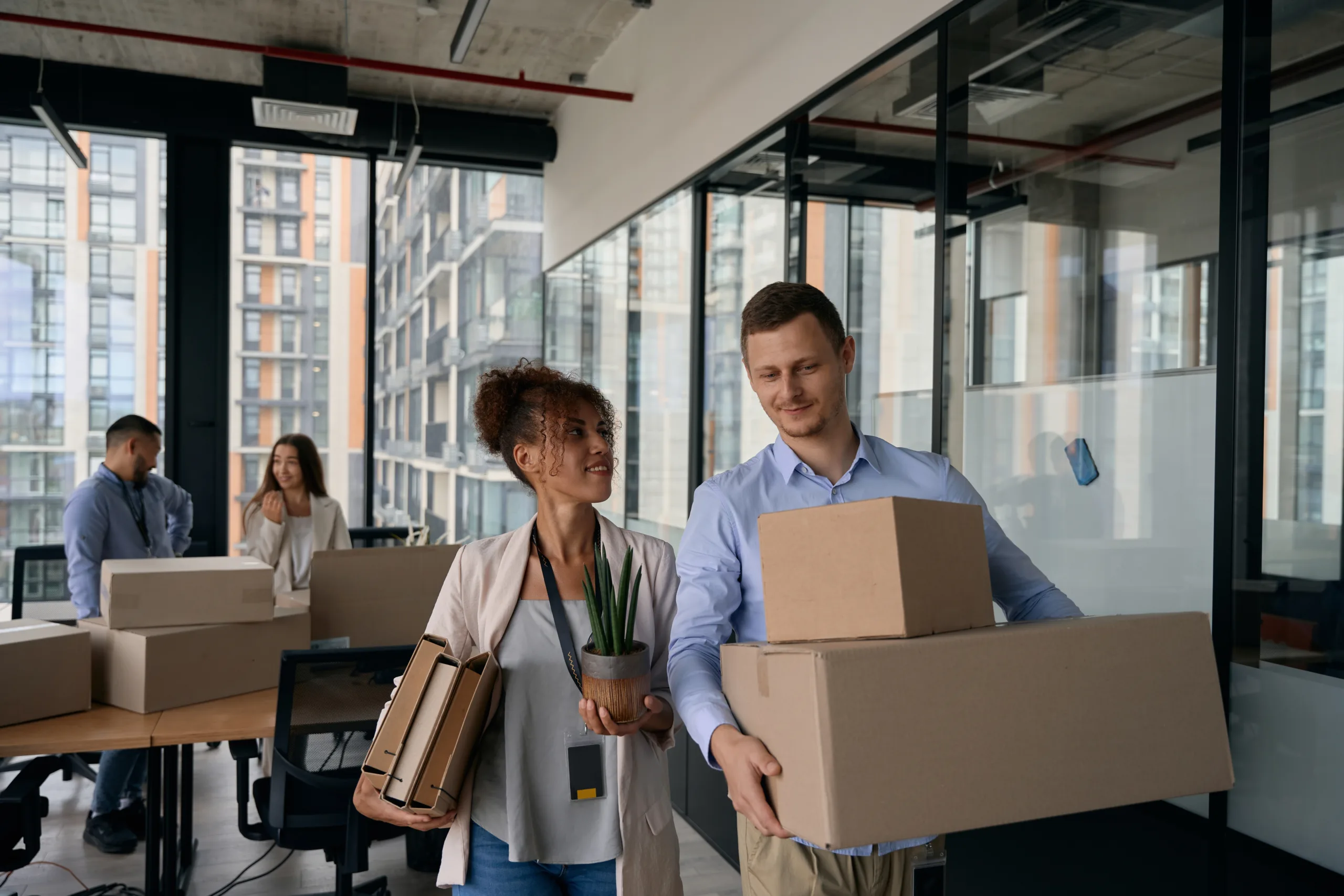 Young business professionals carrying boxes in an office building